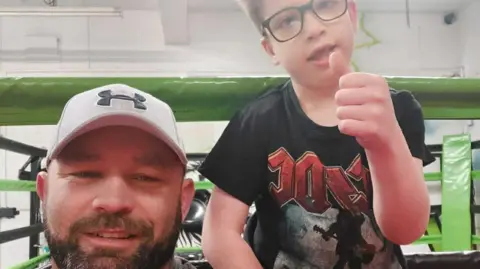 Neil Huntley Neil and Oliver smiling at the camera. Neil is wearing 