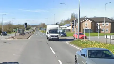 View of Chaddock Lane in Worsley with vehicles passing by a two-storey property.