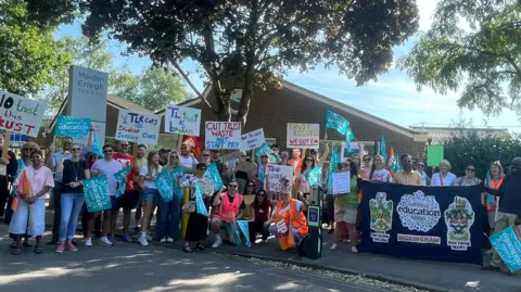 Several teachers striking with pickets outside a school