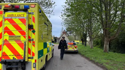 BBC/Sophia Cobby A police officer and an ambulance at the scene of flooding in West Sussex