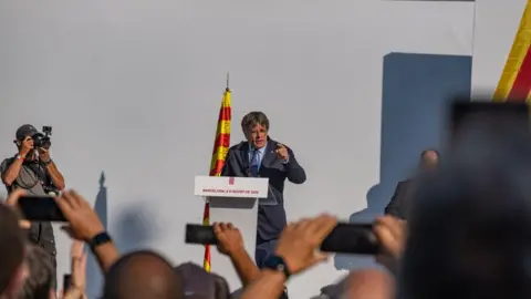 Getty Images Voormalig president van de Generalitat van Catalonië Carles Puigdemont op het podium terwijl hij een arrestatiebevel trotseert dat is uitgevaardigd door het Spaanse rechtssysteem