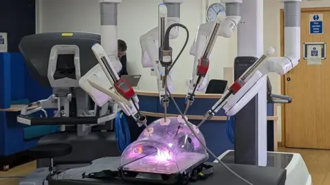 The machine looks like a plastic container with purple light inside, with lots of metal rods poking into it.