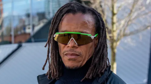 Edgar Davids in a coat and sunglasses