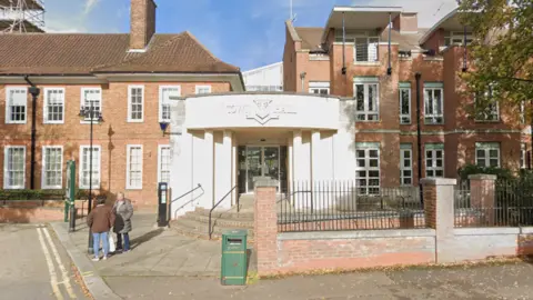 A brick town hall building on a sunny day. The entrance is white. 