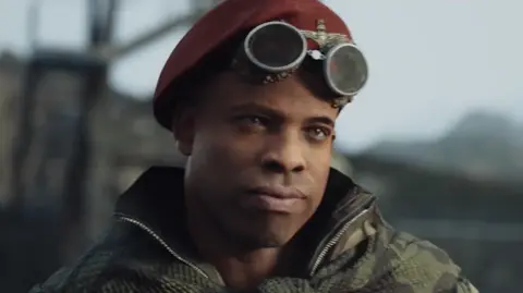 IGN Lt Arthur Kingsley stands gazing to one side in a scene from the video game Call of Duty: Vanguard. He wears a soldier's uniform and a red beret.