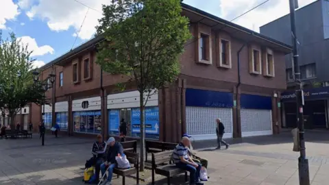 A closed former Boots store occupying a corner plot in a modern building