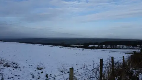 Ian Fergusson Snowy scenes on the Mendip Hills, with a barren, cold vista looking out to lower ground of North Somerset beyond, where no snow is visible. On this day in January 2015, snow only fell and settled on higher parts of the West Country.