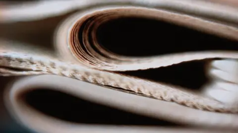 Getty Images A close up of a pile of folded newspapers.