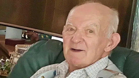 Bedfordshire Constable Paul Swales looks at the camera. He is balding, sitting on a green chair and wearing a checkered shirt.