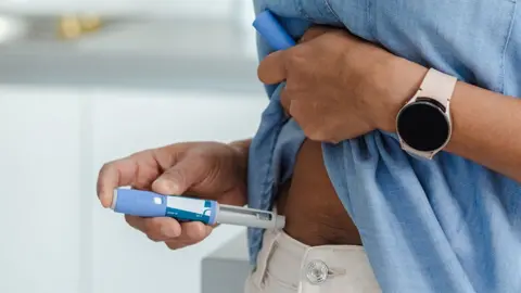 Getty Images A close up of someone self-administering an injection into their stomach