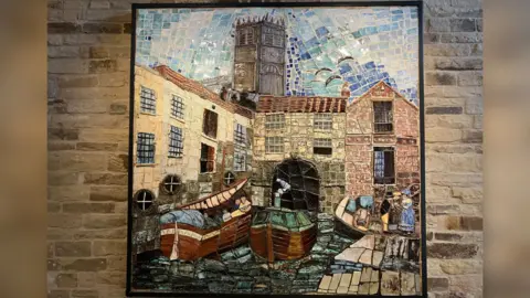 BBC The colourful mural against a stone wall