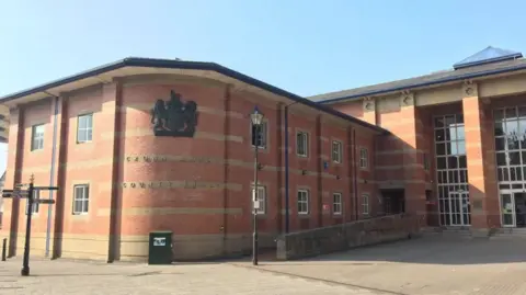 A large red brick building with a number of large windows and a sign stating Crown Court and County Court.