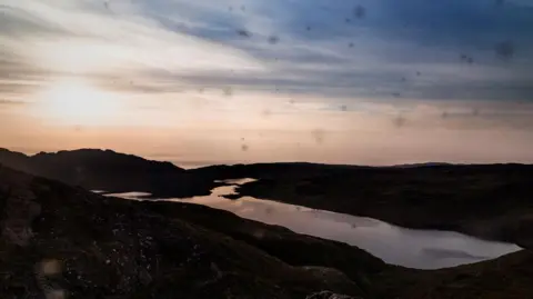 Louise Love Midgies cover the lense of a camera like little blurry dots in a picture taken near Torridon