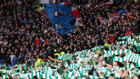 Getty Images Celtic fans many waving green and white scarfs with a net separating them from Rangers fan many wearing red, white and blue