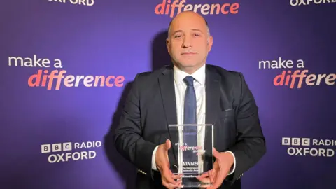 Mahmut Gunaydin standing in front of a purple make a difference backgrounding