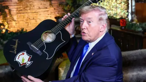 US President Donald Trump holds up a guitar on a visit to Graceland in Memphis, Tennessee, USA.