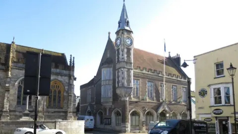 Dorchester Corn Exchange - a grand, stone, gothic-style building from the late 19th-century with a tall pointed clocktower on the corner.