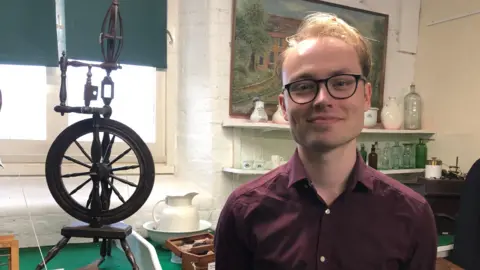 Jon Wright/BBC Elian Shipp stands in front of artifacts inside Felixstowe museum