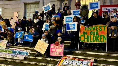 Suzanne Trotter Campaigners carry banners on the steps that read "invest in our children" And "save our children's centers"