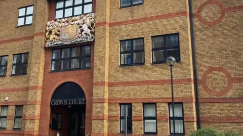 Brian Farmer/BBC St Albans Crown Court. A modern, red-brick building with the words "CROWN COURT" above the entrance door. 