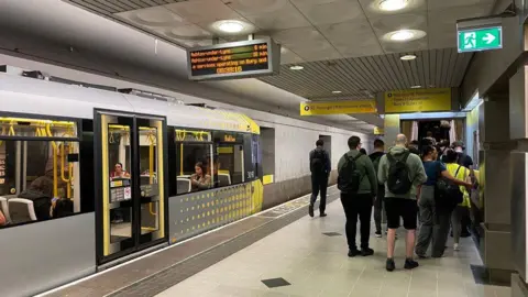 MRIGNAVY/GEOGRAPH Commuters crowd the bottom of an escalator at the end of a tram metro station at Manchester Piccadilly 