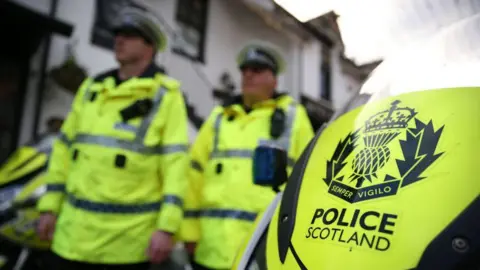 Two out of focus police officers standing behind a police motorbike 