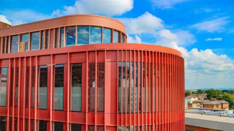 The top two floors of the New Forum. It has red walls and big windows. In the background is a view of Gloucester.