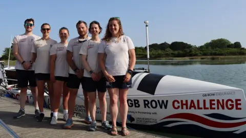 South East Coast Ambulance Service The image shows six people posing in front of a large rowing boat.