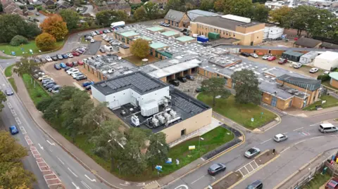 Aerial image of the Queen Elizabeth Hospital, showing low-level buildings and car parks 