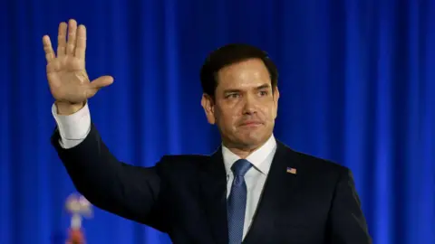 Getty Images Man wearing suit waves his hand