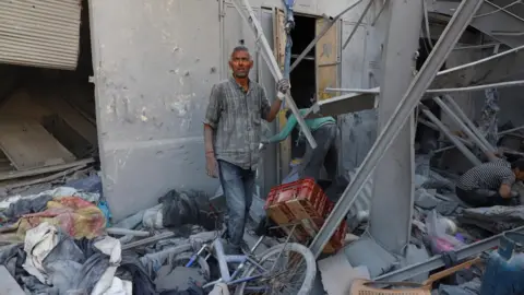 Reuters Palestinian man Mohammed Hajjaj stands amid the ruins of a building sheltering displaced families near Firas market in Gaza City, which was destroyed in an Israeli air strike (24 September 2025)
