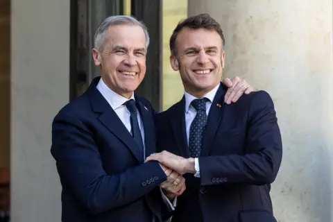 French President Emmanuel Macron (R) shakes hand with Canadian Prime Minister Mark Carney (L) at the Elysee Palace in Paris