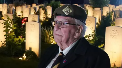 PA Media D-Day veteran Sergeant Richard Brock sits in front of some of the 4,600 lit headstones during the Commonwealth War Graves Commission's Great Vigil to mark the 80th anniversary of D-Day at the Bayeux War Cemetery in Normandy.