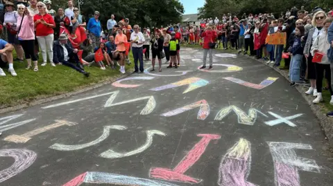 Crowds gathered alongside the raceway, which has the words Go Cav Manx Missile written on it in multicoloured chalk.