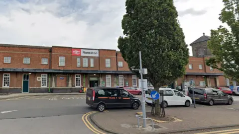 Google Nuneaton Railway Station, a brick building with a taxi rank in front and two trees