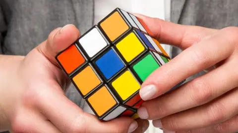 A rubiks cube in the hands of a child with a grey tshirt