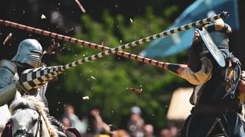 Two knights wearing armour jousting while riding horses