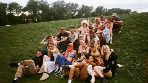 An image of the Truth Tribe music collective sitting on grass. 