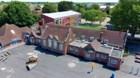 An aerial photograph of Stanway Primary School, a red brick building, and its playground.