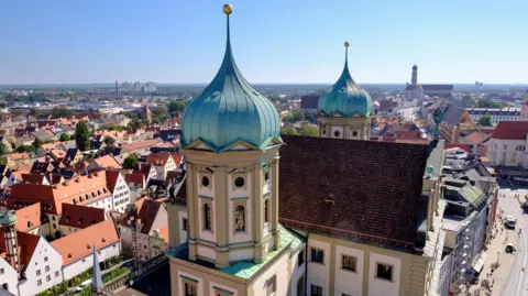A bird's eye view of part of Augsburg, including its town hall, Maximilian Street and St Ulrich and Afra Church.