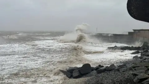 BBC Weather Watchers Giant waves crash against a sea wall.