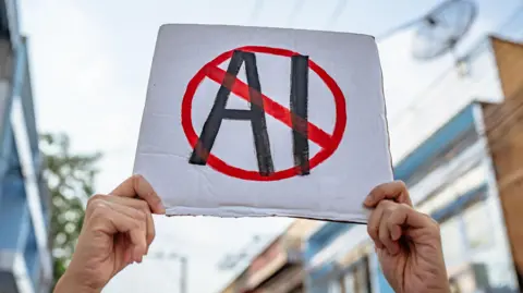 Getty A hand written sign with the letters AI with a red circle round it and a red line though it is head aloft