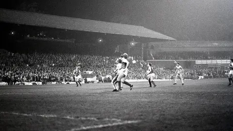 Steve Daniels A black and white image of a game at the Manor Ground.