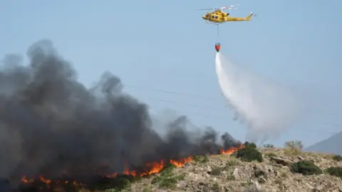 A helicopter works to extinguish flames amid deadly wildfires affecting Almeria province