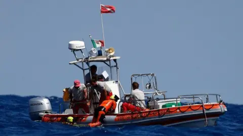 Reuters Diver hanging on to side of orange boat