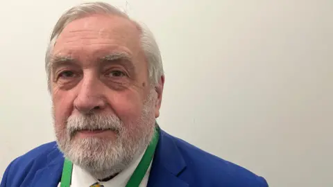 A head-and-shoulders image of a man with grey hair and a beard