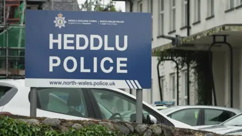 Outside Caernarfon police station. A blue sign has "Heddlu Police" written on it