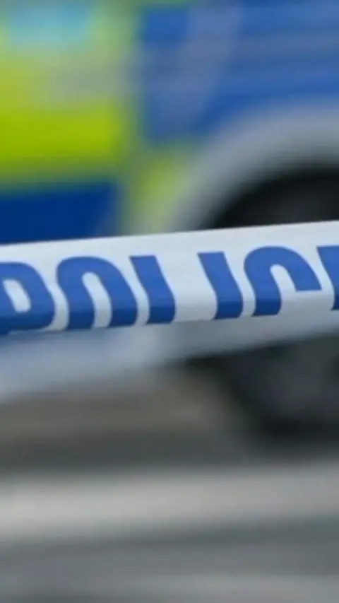 A close up of police tape and a police car