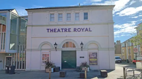 The Theatre Royal building in Dumfries with a white facade and a green door