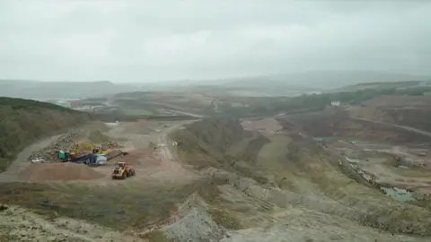 A general view of a mine showing machinery and dirt roads on a cloudy day.